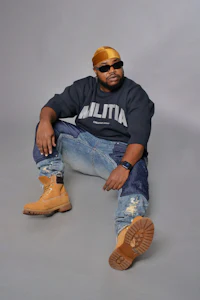 a man sitting on the ground wearing a hat and jeans