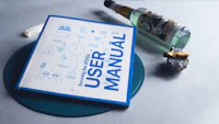 a user manual on a table next to a bottle of liquor